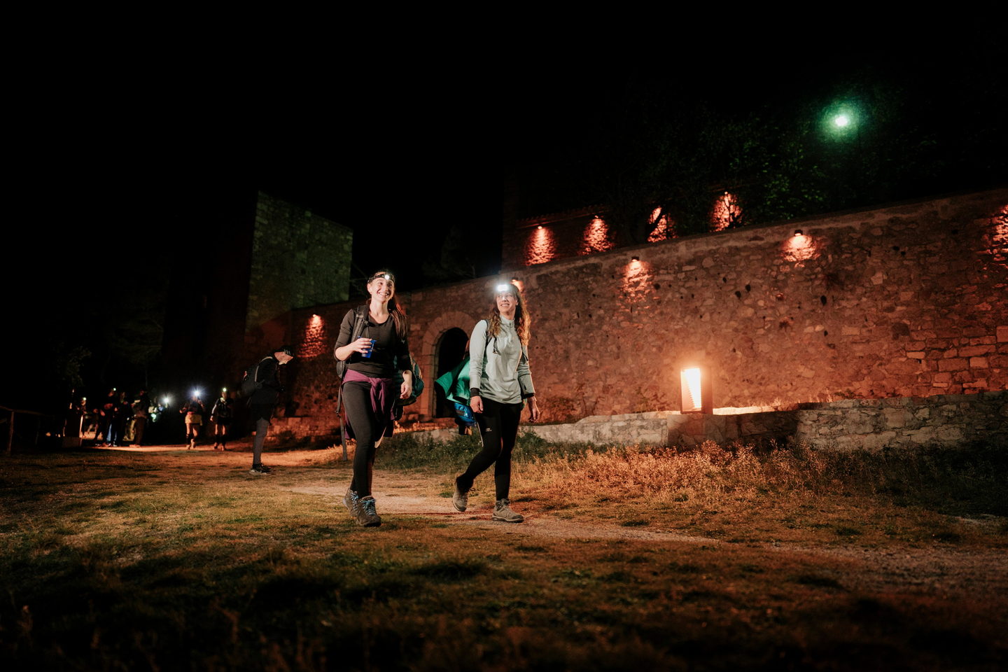 Dos caminants amb frontal al mur d’espelmes del Santuari